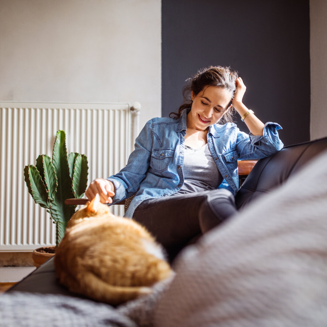 Woman relaxing on sofa, with her cat, in the living room